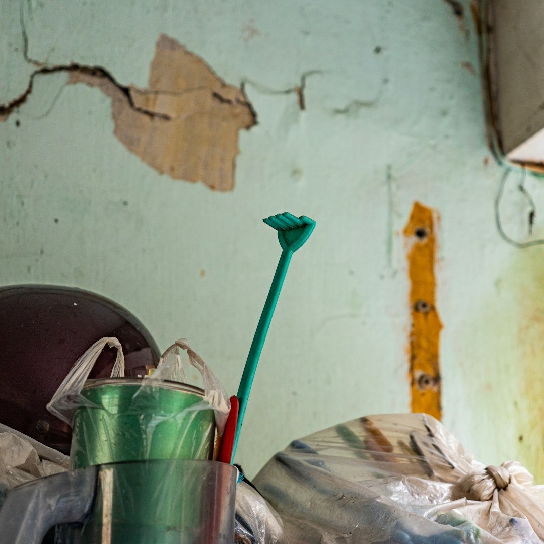 Green hand shaped back scratcher standing in a pile of clutter.